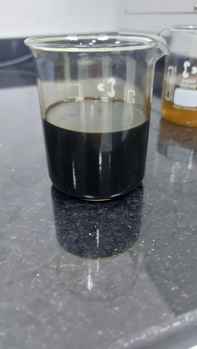 A dark off-spec sample in a beaker on the black granite bench