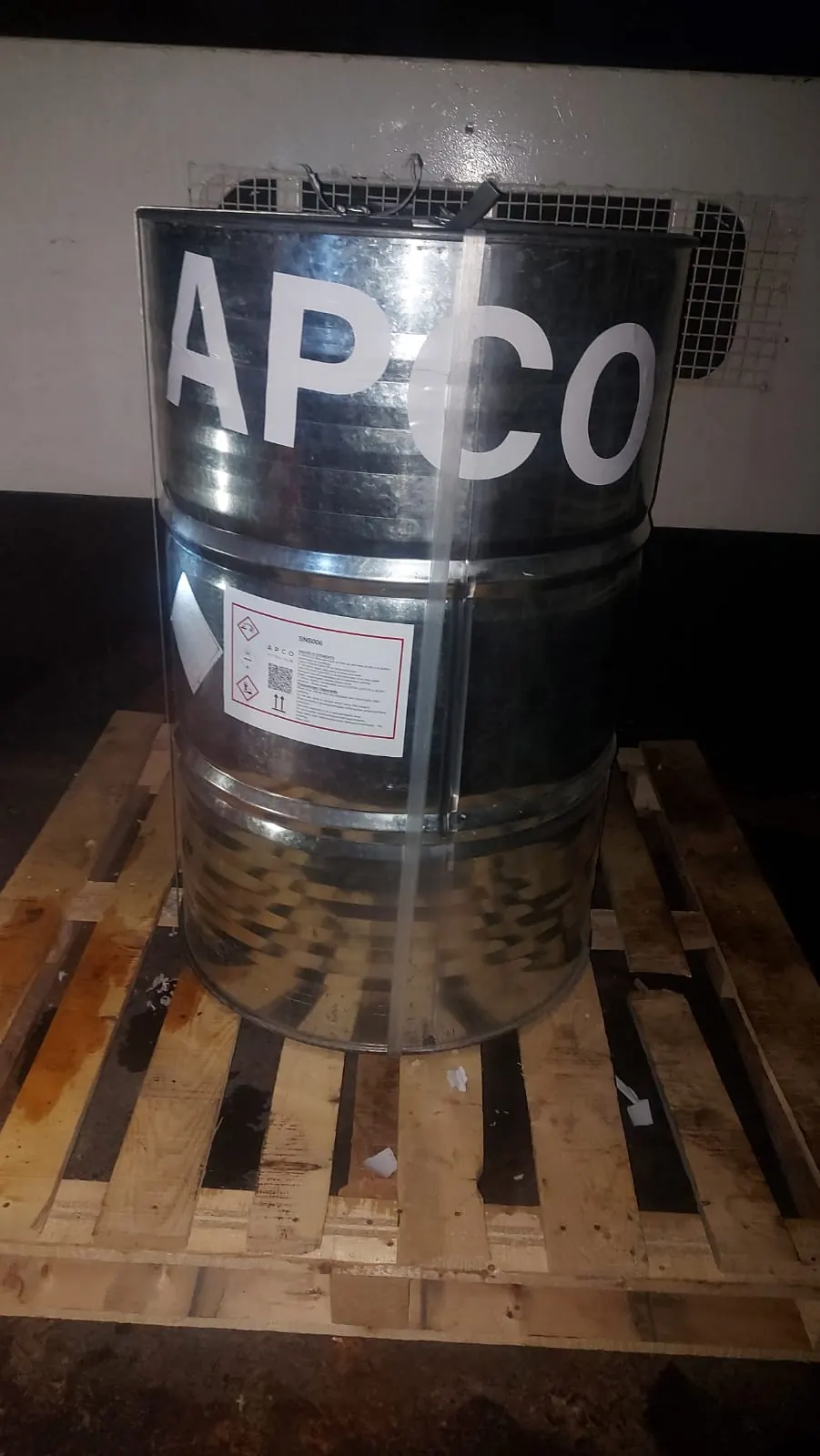 A steel drum stencilled APCO on a wooden pallet in the warehouse